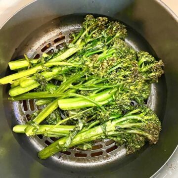 cooked broccolini in a Ninja Foodi Air Fryer basket