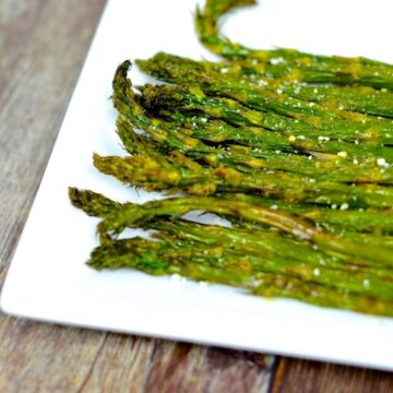Cooked frozen air fryer asparagus served in a white plate on a brown table