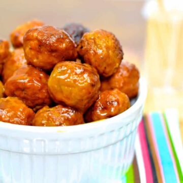 cooked air fryer chicken meatballs in a white bowl sitting on a stripped napkin