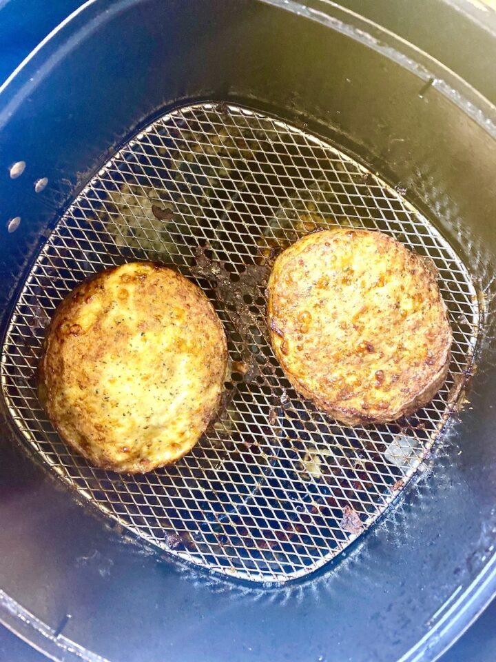 cooked chicken burger patties in air fryer basket