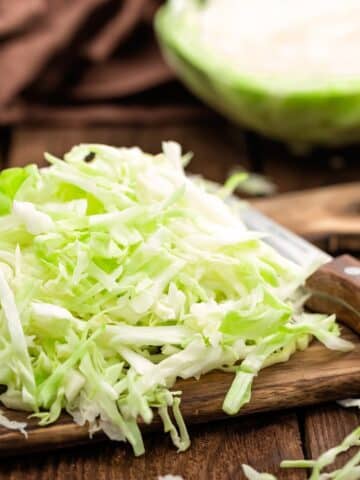 Shredded cabbage on a wooden cutting board.